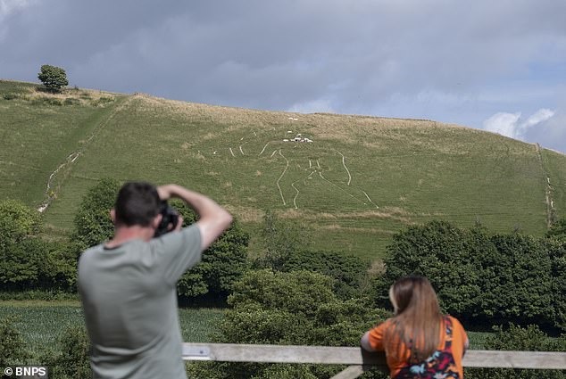 Volunteers apply 17 tonnes of chalk to restore fading Cerne Abbas Giant.